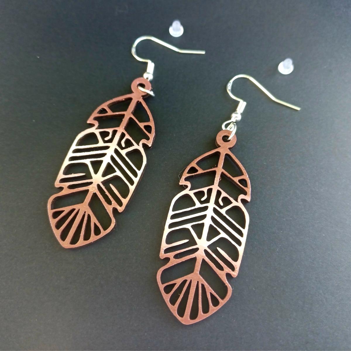 Boucles d'oreilles pendantes en bois ajouré en forme de plume de couleur marron avec crochets argentés hypoallergéniques
