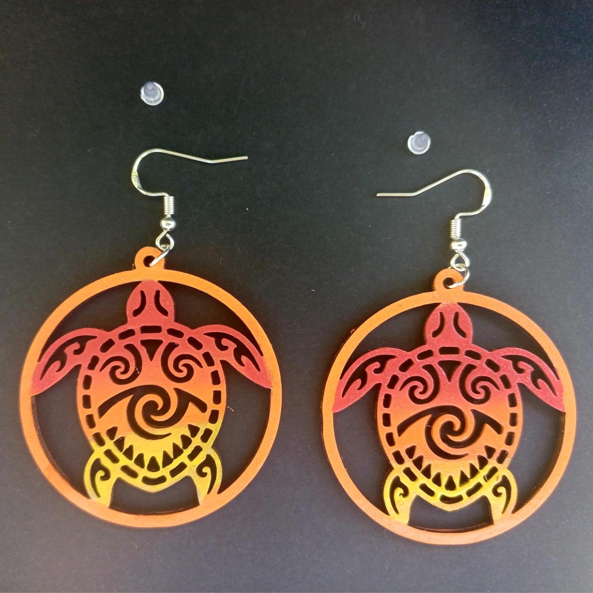 Boucles d'oreilles pendantes rondes en bois ajouré avec motif de tortue tribale en dégradé rouge, orange et jaune et bouchons silicone