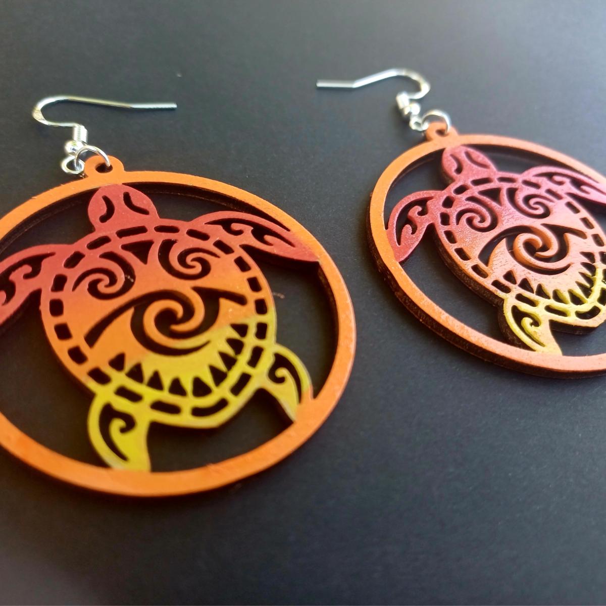 Boucles d'oreilles pendantes rondes en bois ajouré avec motif de tortue maorie en dégradé rouge, orange et jaune