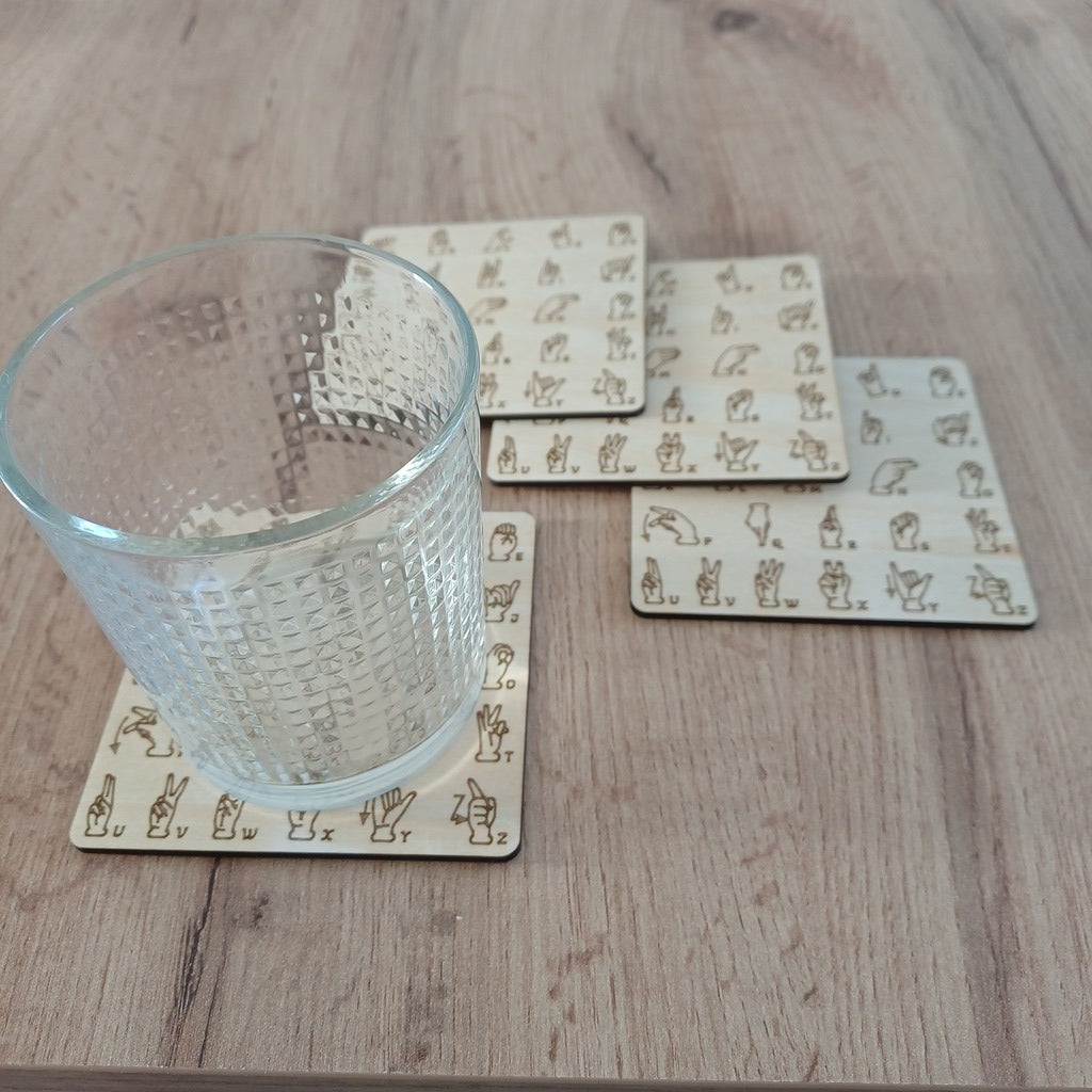 Lot de 4 sous-verre en bois gravé alphabet en Langue des signes française et un verre transparent posé dessus